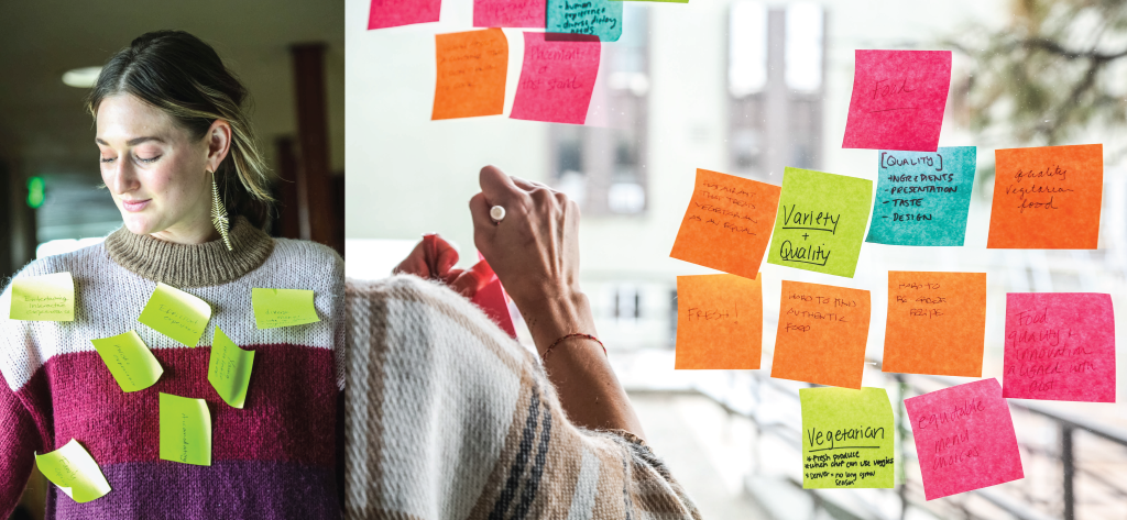 A woman with Post-It Notes stuck to her sweater next to a window covered in colorful Post-It Notes.
