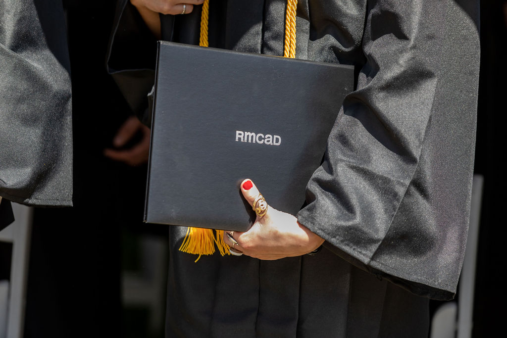 Close up of a RMCAD student with red nail polish holding their diploma.