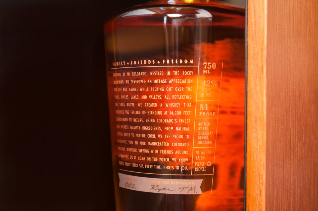 Close up of Branch and Barrel Whiskey back label on the bottle designed by EBD that read Family + Friends + Freedom.
