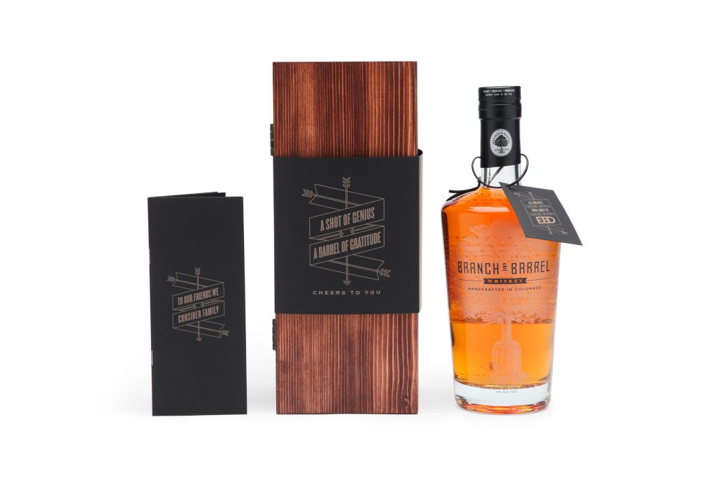 Branch and Barrel Whiskey pamphlet, wooden box and glass bottle designed by EBD standing next to each other against a white background.